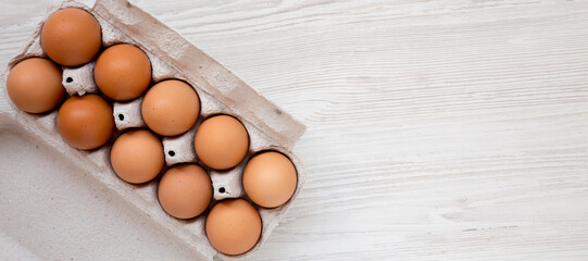 Raw Brown Eggs in a paper box, top view. Flat lay, overhead, from above. Space for text.