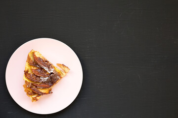 Homemade Apple Dutch Pannekoek Pancake on a pink plate on a black background, top view. Flat lay, overhead, from above. Space for text.