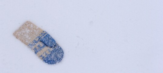 One knitted mitten lost by somebody on the snow. The concept of wintertime, holidays.