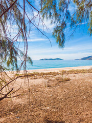 Deep blue turquoise sea panorama with long sand beach with forest under cloudy sky background. Tropical holiday paradise, the end of quarantine Covid 19 isolation - beginning of normal life again