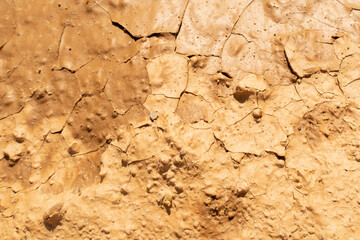 Cracked drought clay ground during the dry season. Bright yellow or orange sand color land with cracks texture. Stock background photo
