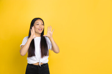 Shouting. Portrait of young asian woman isolated on yellow studio background. Stylish, trendy. Beautiful brunette model. Human emotions, facial expression, sales, ad, shopping concept. Copyspace.