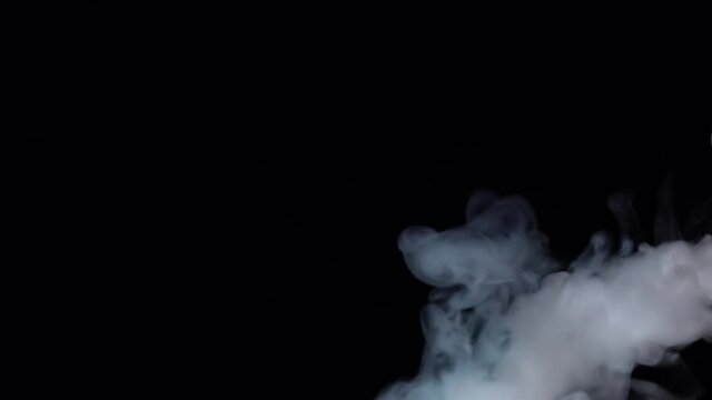White smoke floating through space against black background. Mist, smoke , vapor, fog effect. Slow motion