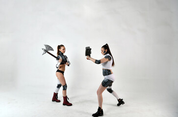 beautiful girls in costumes of robots quarreled and fight with a battle ax and a war hammer