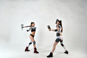 beautiful girls in costumes of robots quarreled and fight with a battle ax and a war hammer