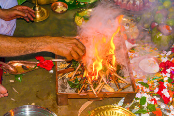Hand of a hindu brahmin priest worshiping hindu God by performing yajna ritual by adding ghee in flame.