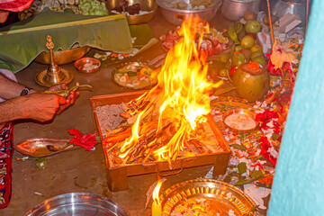 Hand of a hindu brahmin priest worshiping hindu God by performing yajna ritual by adding ghee in...