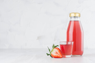 Fresh pink strawberry juice in glass bottle template with  glass, fruit slices on wood table and white background with copy space.