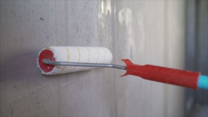 A worker primers the walls with a brush. Wall painting with primer paint with a large brush