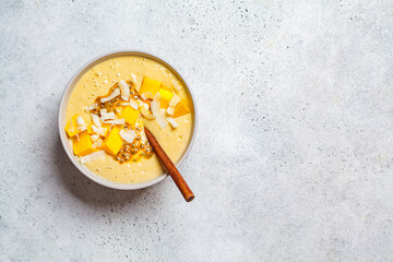 Tropical smoothie bowl with mango, passion fruit and coconut, light background.
