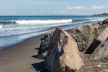 Volcanic beach and rocks of Keramas Beach (Pantai Keramas), Gianyar, Bali, Indonesia.