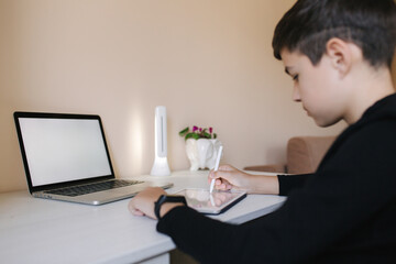 Teenage boy studing on paltip at home. Young boy play online games at home. Study in quarantine. Happy schoolboy during qurantine