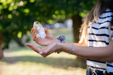Young millennial woman sanitize his hands with antibacterial gel in bottle disposable against the bacteria and virus of Coronavirus, Covid-19