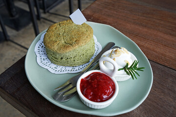 Close up Matcha green tea scone served with clotted curd cream and strawberry jam