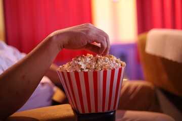 Close up man hand with popcorn bucket.