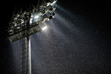 A swarm of mosquitoes and other night insects fly in the light of a stadium reflector near a big...