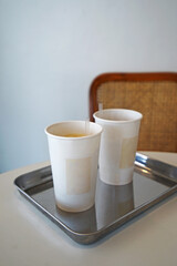 Paper cups of iced coffee on aluminium tray and white table