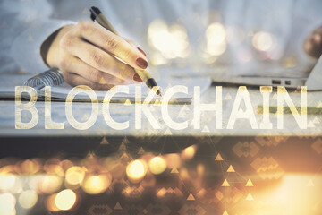 Cryptocurrency hologram over woman's hands writing background. Concept of blockchain. Double...