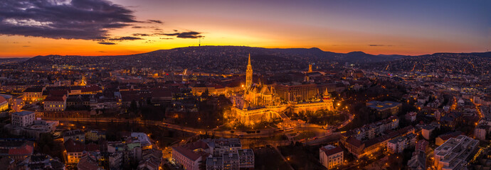 Aerial panorama drone shot of lighted Matthias Churh Fisherman's Bastion on Buda Hill in Budapest sunset time