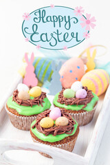 Homemade carrot cake muffins decorated with cream cheese frosting and Easter chocolate eggs, hand drawn lettering Happy Easter, vertical