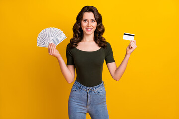 Portrait of her she nice attractive lovely cheerful cheery wavy-haired girl holding in hands bank card cash wealth isolated on bright vivid shine vibrant yellow color background