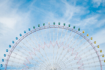 half of Ferris wheel in Osaka, Japan with a bright sky.