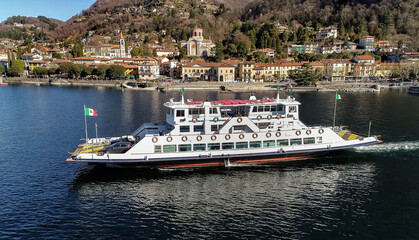 Aerial drone view of ferry boat that leaves from the port of Laveno Mombello. Passenger transport with vehicles, navigation on Lake Maggiore, Italy