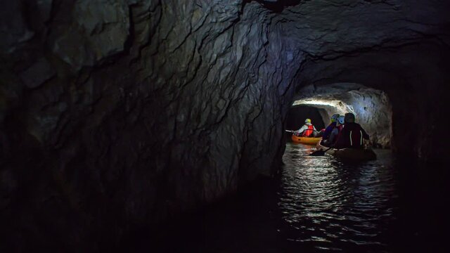 A follow shot of a group of people entering a dark cave by boats.