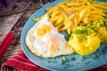 Fried egg served with boiled potatoes and yellow beans.