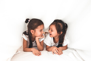 two girls reading under blanket