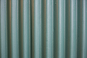 filled frame close up background wallpaper shot of a galvanized green metal sheet wall with vertical lines and black shadows