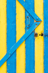 Une porte en bois jaune et bleue. Une façade de maison traditionnelle en bois jaune et bleu. Des lattes de couleurs comme le drapeau de la Suède.