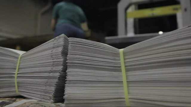 Worker carrying stack of newspaper in a Printing Press Factory