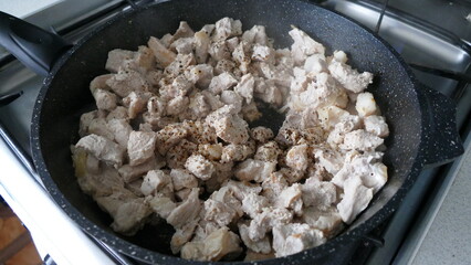 pieces of meat are fried in a frying pan