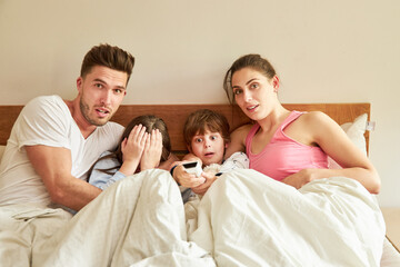 Parents and children in bed with remote control