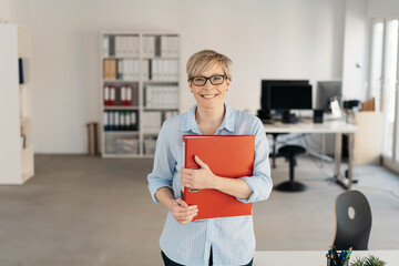 Smiling happy businesswoman clutching a binder