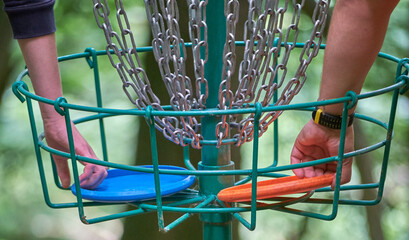 Hands in the disc golf basket