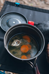 A small portable tourist pot, with a fish soup, a fish dish. It stands on the table. camping breakfast. Vertical photo