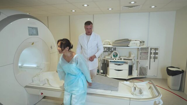 Magnetic resonance imaging, adult man doctor performs a magnetic tomographic examination of a young asian woman, MRI, modern technologies in medicine.