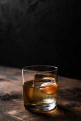Old fashioned cocktail in a rocks glass with a big ice cube, back light