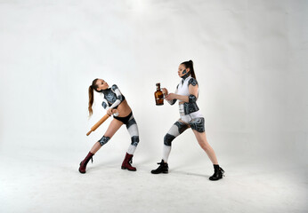 beautiful girls in costumes of robots quarreled and fight with a rolling pin and a big bottle