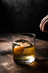 Citrus oil expression shot, a rocks glass with old fashioned cocktail, back light