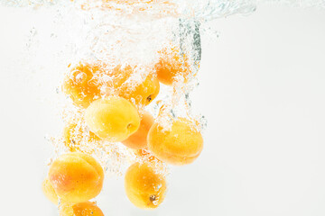 Fototapeta na wymiar Apricots are falling in the clear water with splash.