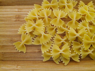 Pasta bows scattered on a wooden board.