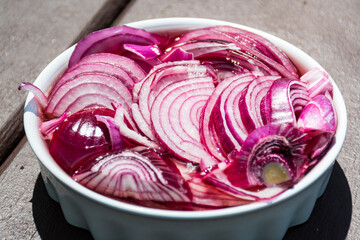 Red onions are cultivars of the onion (Allium cepa) with purplish-red skin and white flesh tinged with red, salad in a pot on the table, healthy food