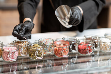Chef mixing different ice cream toppings for sprinkling on the chocolate ice cream at the shop, close-up