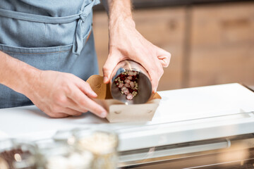 Seller mixing different ice cream toppings for sprinkling on the chocolate ice cream at the shop, close-up