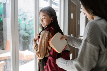 mother help preparing lunch box to her daughter junior high school student before going to school