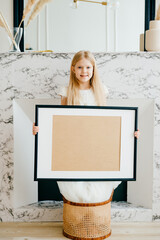 Beautiful young girl stands with a blanck picture, place for inscriptions