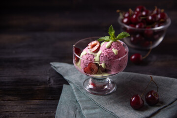 Cherry ice cream in a glass bowl on a dark wooden table. Rustic summer refreshing dessert.